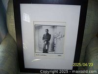 Framed black and white 8x10 photo of Glen Campbell, signed by Glen Campbell, resting on a chair.