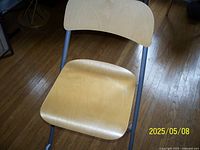 Top view showing light wood seat and backrest with minor blemishes and gray metal frame.