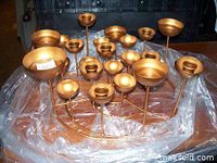 Photo of a large gold-tone metal decorative centerpiece with multiple candle holder cups arranged on curved metal stems of varying heights, approx. 24 inches wide.