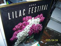 Framed Lilac Festival poster from 2009 with pink and white lilac flowers on black background.