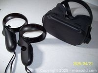 Photo shows a Metaquest VR headset and two wireless controllers on a white surface. Controllers have visible hairline cracks which have been glued.