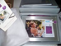 Photo of Philips digital photo frame in box showing front of frame with sample image displayed and part of packaging.