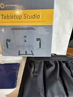 Box showing Pro Master Tabletop Studio product, displaying studio setup with lights and camera stand.