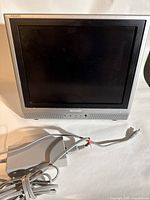 Front view of Sharp Aquos 13-inch portable monitor showing screen and attached power cord and adapter.