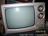 Photo of a vintage black and white portable TV showing the front, including the screen, two channel tuner dials, two control knobs, and the cream-colored casing.