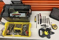 Two open toolboxes with assorted hand tools and hardware inside, including files, screwdrivers, measuring tapes, clamps, drill bits, chisels, utility knife, and small tools.