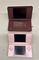 Top view of opened burgundy Nintendo DSXL and pink Nintendo DS Lite showing dual screens and controls