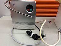 Front view of silver ionizer unit showing digital display and Power/Mode buttons with attached gooseneck spout.