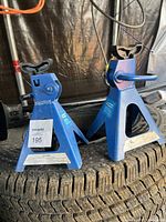 Two blue 4 ton car jacks placed on a tire, showing front and side views with lifting saddle and ratchet mechanism visible.