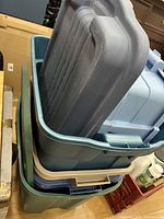 Stack of stacked plastic storage bins of different colors and sizes with lids on top.