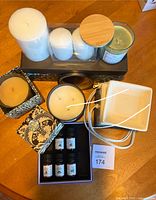 Wide view showing various candles on and around a tray, the ceramic dish, and the box of essential oils.