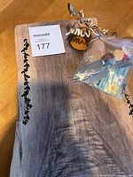 Top-down view of entire live edge wooden board with dark natural edge and some accessories on top with a MaxSold lot number.