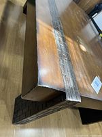 Close-up of the corner of the table showing the carved wooden band design on the edge and leg.