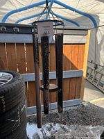 Photo of large metal wind chimes with four worn painted tubes hanging from wooden top