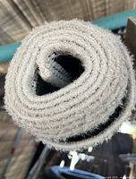 Close-up image of rolled up light beige woven rug material.