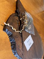 Full view of the dark wood live edge charcuterie board lying flat, showing its texture and included hardware.