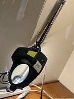 Heavy duty black magnifying glass with mounted lamp arm and attached power cord.