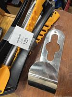 Folded parts of the clothes rack including yellow and black plastic handles and stainless steel rods, showing the compactness and portability of the rack.