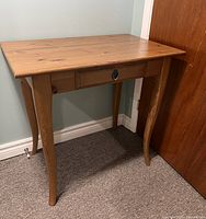 Image showing full pale wood desk with rectangular top, single drawer with round metal pull, and curved legs.
