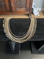 Front view of the multi-layered vintage chain necklace displaying the different chain strand styles on a black jewelry stand.