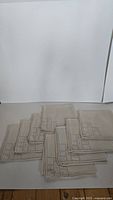 Set of eight folded linen napkins showing the edges with hand embroidery and hemstitching