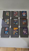 Overview photo showing all 9 NES game cartridges laid out in grid. Labels readable showing game titles and art.