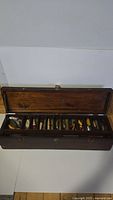Open wooden tackle box showing ten compartments each with a lure