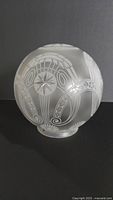 Front view of the antique cut glass globe lamp shade showing intricate starburst and floral cut designs with a frosted background.