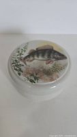 Top view of the round ceramic container showing fish design on lid