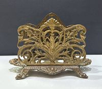 Front view of the solid brass letter holder showing detailed Art Nouveau floral and scroll cutout design.
