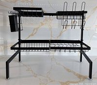 Front view of the black metal dish drying rack showing the two-tier design and utensil holder