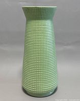 Front view of green textured ceramic vase with flared lip and grid relief pattern.