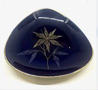Front angled view of triangular cobalt blue ceramic plate featuring gold and silver leaf design and gold rim.