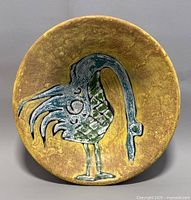 Top view of the bowl showing yellow interior with blue and green bird design, textured surface.