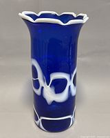 Front view of cobalt blue glass vase with white swirls and scalloped rim