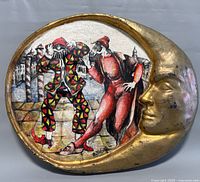 Front view of the oval-shaped mixed media wall art with gold crescent moon face and theatrical characters painted inside.