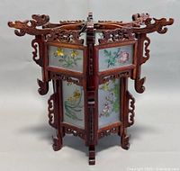 Front view showing carved top and two painted glass panels of yellow flowers and green leaves.