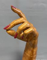 Close-up side view of carved wooden mannequin hand showing detailed fingers and red fingernails.