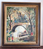 Framed painting showing the overall artwork with bridge, water, trees, and buildings.