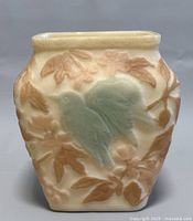 Front view of the cream-colored Consolidated Glass Company vase featuring a green-purple bird with brown leaves.