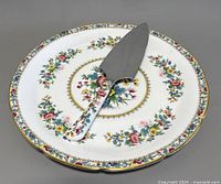Cake plate with server on top showing floral pattern and gold trim.