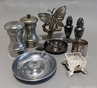 Wide shot of the full lot showing pewter salt and pepper shakers, butterfly figurine, dishes, glass holder, and other pewter items.