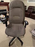 Front view of a brown/grey fabric office chair with padded seat and backrest, plastic armrests, and plastic base with caster wheels.