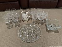 Full view of the 5 red wine glasses, 7 white wine glasses, ceramic gravy pitcher, crystal serving platter, and candy bowl on carpeted floor.