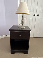 Brown black wooden nightstand with drawer and open cubby space. Nightstand drawer shown open revealing light wood interior.