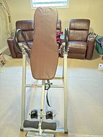 Front view of inversion table upright showing padded backrest, ankle support and handles