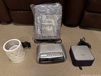 Two clock radios, one silver Panasonic RC-3288 and one grey Philips NFC, along with a pack of folded jersey single sheets and a wax melt warmer.