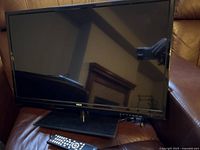 28-inch RCA HD TV on stand with RCA remote control in front