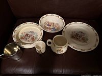 Five-piece ceramic children's dishware set including two bowls, a dinner plate, a handled mug, and a small egg cup, all with Royal Doulton Bunnykins design and rabbit border.