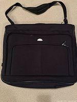 Front view of medium-sized black fabric garment bag with multiple zippered pockets and silver Samsonite logo